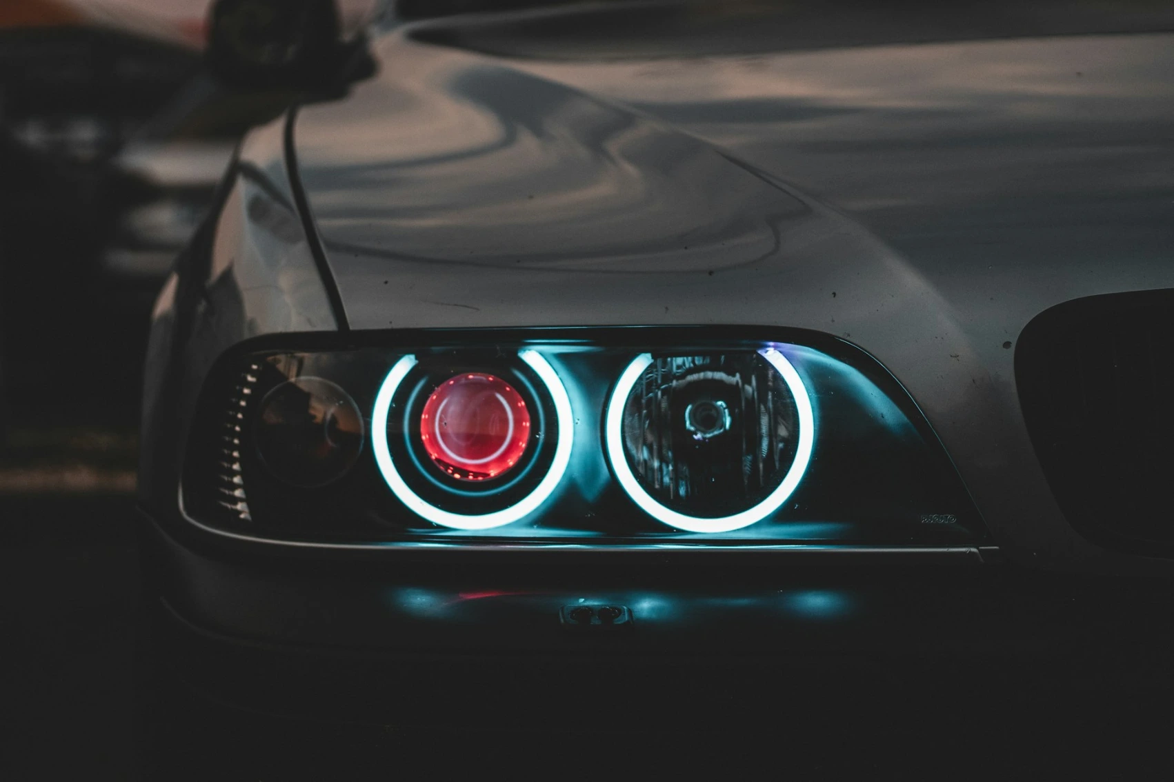 Close-up of a car headlight with glowing blue circular rings and red center